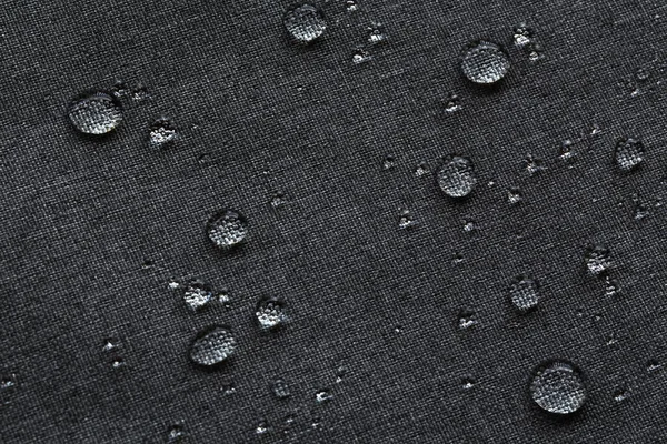 Waterproof droplets on fabric. Black Canvas Polyester texture synthetical for background. Black polyester textile backdrop for interior art design or add text message.