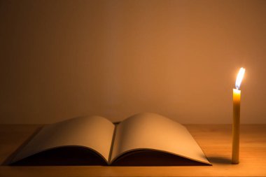 Candle light with note book on the wooden table in the dark night. picture for art work design or add text message.