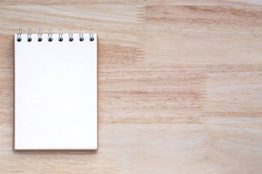 Tahta masanın üzerinde beyaz not defteri açık sayfalar.