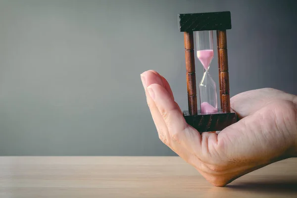 Concept image of management at the time of life. Abstract hourglass on man hand. passing time in a countdown sandglass with copy space for add text.
