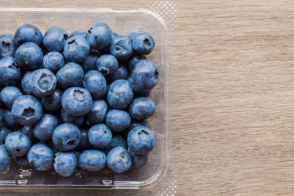 Fresh Blue berries on plastic packaging, Healthy sweet juicy berries on wood table for add text design.
