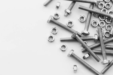 Beyaz arka planda vidalar, paslanmaz fındıklar ve cıvatalar. Metin iletisi için üst görünüm Resim alanı, web sitesi için düz konum flaması.