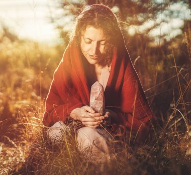 Beautiful shaman woman in nature and ceremony of the earth. Woman holding a large crystal of rosary in her hands clipart