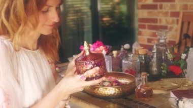 Gerekli yağı hazırlamak için gül çiçeği. Spa ve aromaterapi. Kadın gül yaprakları gibi kokuyor. Adaçayı tütsülü arka plan, tören alanı