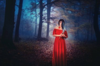 Derin mistik sisli ormanda, elinde geyik boynuzuyla tüyleri olan bir şaman kadın. Törenler sırasında görüntülemek için kullanılan tüy yelpazesi