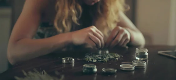 woman prepares herbs for tobacco with the help of a herb grinder to grind a cannabis