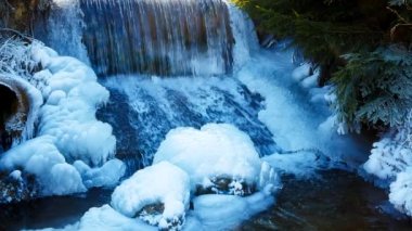 Winter scene with water falling from icy rocks. Blue color