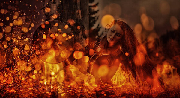 Beautiful shamanic girl playing on shaman frame drum in the nature. Fire background
