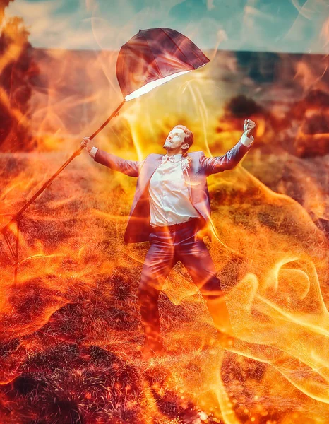 stock image A lone figure defiantly shelters under an umbrella, confronting a blazing inferno. A symbol of pyrrhic victory, this epic fantasy stock photo evokes a sense of triumph amidst destruction.