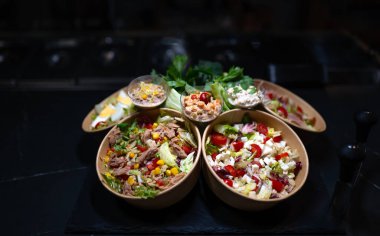 Siyah arka planda farklı salata türleri.