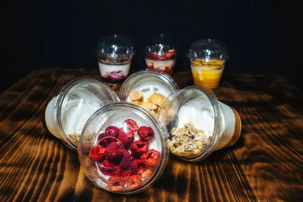 Fruit yogurts on black background. Healthy breakfast on the wooden table
