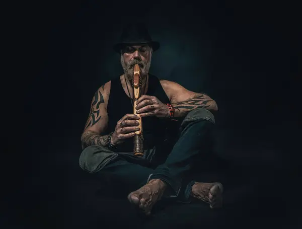 Man plays a native american flute in a studio, atelier photos, black background