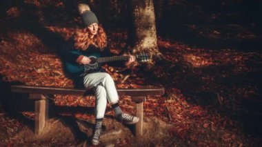 Sonbahar manzarasında gitar çalan güzel bir kadın. Döngü Canlandırması