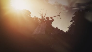 Hokkabaz silueti gün batımına karşı gösteri yapıyor, dinamik hareket ve zarafet sergiliyor.
