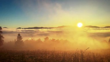 Çekimin sonunda manzaraya bakan bir kadınla dolu sisli bir sonbahar manzarasında parlayan huzurlu ve güzel bir gün doğumu.