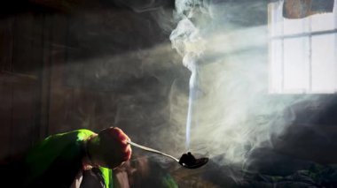 Güneş doğarken bir dağ kulübesinde eski bir pencereden süzülen gizemli ışık elinde tütsüyle yeşil bir uyku tulumu içindeki bir kadının üzerine parlıyor.