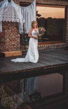 Sunset 'te zarif bir gelin, zarif bir çiçek buketi tutuyor.