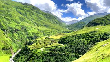Arkaplanda yeşil tepeler ve dağlar