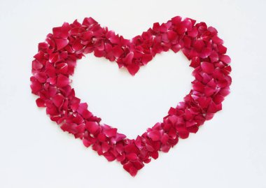 Beyaz arka planda kırmızı gül yapraklarından oluşan romantik bir kalp. Sevgililer Günü dekorasyonu.