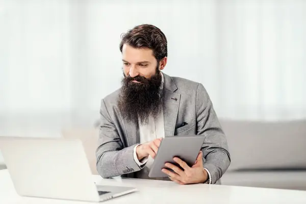 Multitasking Concept Bearded Entrepreneur Using Tablet Looking Laptop His Home — Stock Photo, Image