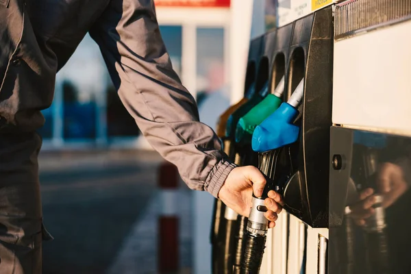 Close up of a gas station worker holding the petrol dispenser.