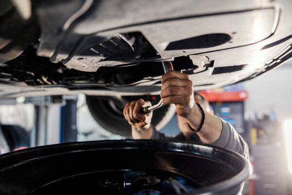 Mechanic's hands using offset spanner on car while standing under it and fixing it. — Stock Image Mechanic Hands Using Offset Spanner Car While Standing Fixing Stock Photo