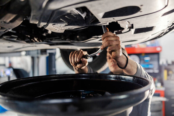 Hands of a mechanic using offset spanner on a bottom of the car while standing at workshop. — Stock Image Hands Mechanic Using Offset Spanner Bottom Car While Standing Workshop Stock Photo