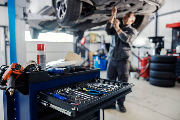 Cropped picture of a mechanic toolbox with tools in drawer with worker repairing car in blurry background at workshop. — Stock Image Cropped Picture Mechanic Toolbox Tools Drawer Worker Repairing Car Blurry Stock Photo