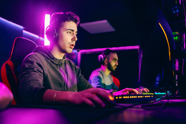 Gamer sitting in dark gaming room with neon lights and playing online games. — Stock Image Gamer Sitting Dark Gaming Room Neon Lights Playing Online Games Stock Image