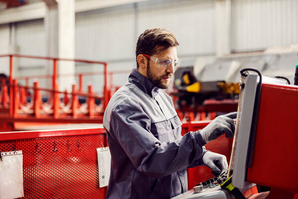 A factory worker is starting the machine and controls it on the dashboard while standing in the facility. — Stock Image Factory Worker Starting Machine Controls Dashboard While Standing Facility Stock Image