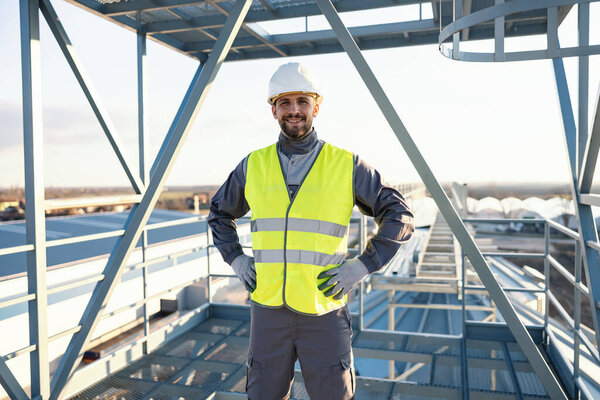 A worker stands proudly on a height outside on metal construction and smiles at the camera. — Stock Image Worker Stands Proudly Height Metal Construction Smiles Camera Royalty Free Stock Images