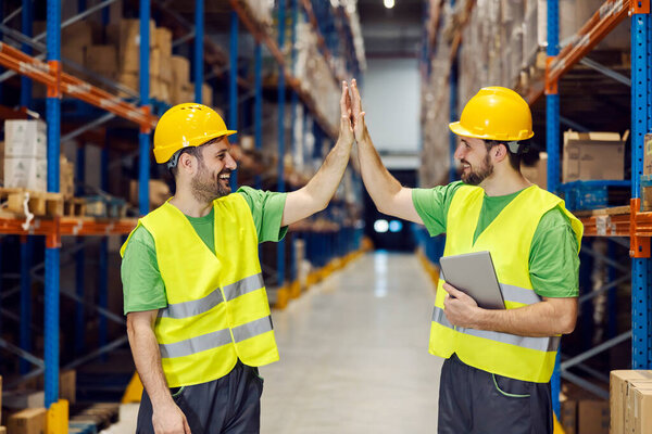 Two storage workers giving high five for teamwork. — Stock Image Two Storage Workers Giving High Five Teamwork Royalty Free Stock Photos