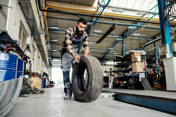 A mechanic rolling tyre in a mechanic's shop and preparing it for installation. — Stock Image Mechanic Rolling Tyre Mechanic Shop Preparing Installation Stock Image
