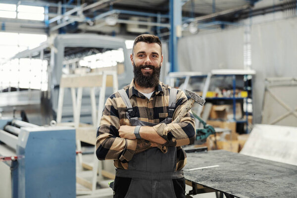 A metallurgy worker with hammer proudly standing in factory and smiling at the camera. — Stock Image Metallurgy Worker Hammer Proudly Standing Factory Smiling Camera Stock Picture