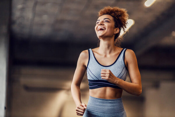 A laughing fit urban runner with curly hair is running in the tunnel. Runner running in a tunnel. — Stock Image Laughing Fit Urban Runner Curly Hair Running Tunnel Runner Running Stock Picture