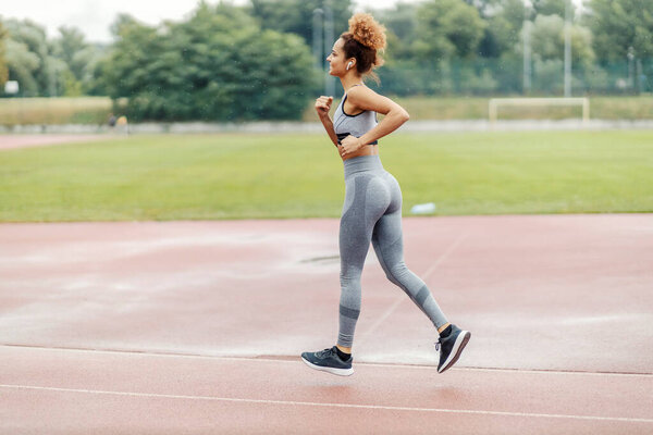 A happy, fit runner runs in the stadium on a rainy day while listening to music. There is always a barrier, you choose if you want to get over it. Runner running in the stadium on a rainy day. — Stock Image Happy Fit Runner Runs Stadium Rainy Day While Listening Music Royalty Free Stock Photos