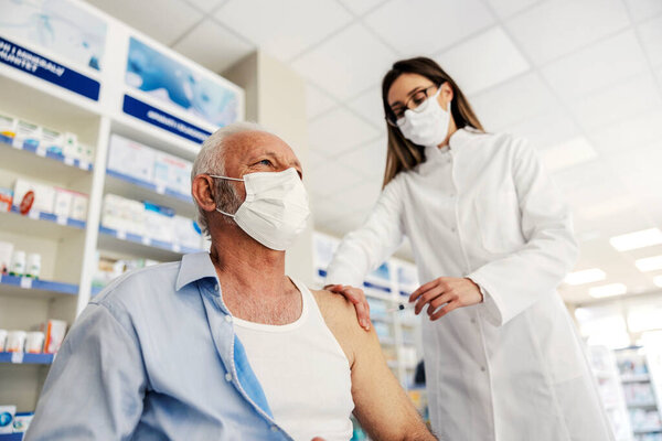 A nurse giving covid vaccine to an old man at pharmacy. — Stock Image Nurse Giving Covid Vaccine Old Man Pharmacy Royalty Free Stock Images