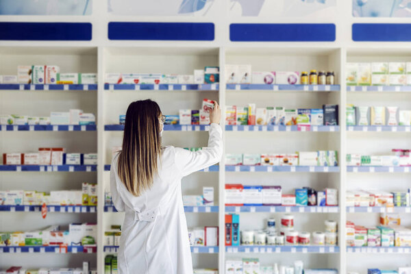 A pharmacist checking on medicines on shelves. — Stock Image Pharmacist Checking Medicines Shelves Royalty Free Stock Images