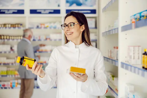 Young Smiling Pharmacist Holding Drugs Showing Camera Stock Picture