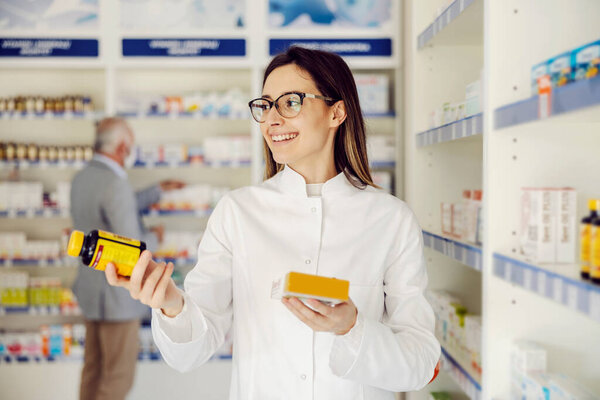 Young Smiling Pharmacist Holding Drugs Showing Camera Stock Picture
