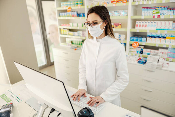 A pharmacy worker typing on computer at pharmacy. — Stock Image Pharmacy Worker Typing Computer Pharmacy Stock Picture