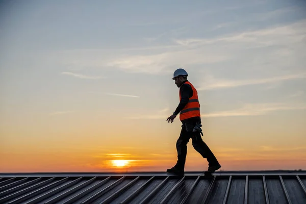 Silhouette of height works worker walking on the rooftop at sunset.