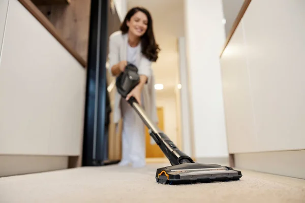 Close up of a woman vacuuming floor at home.