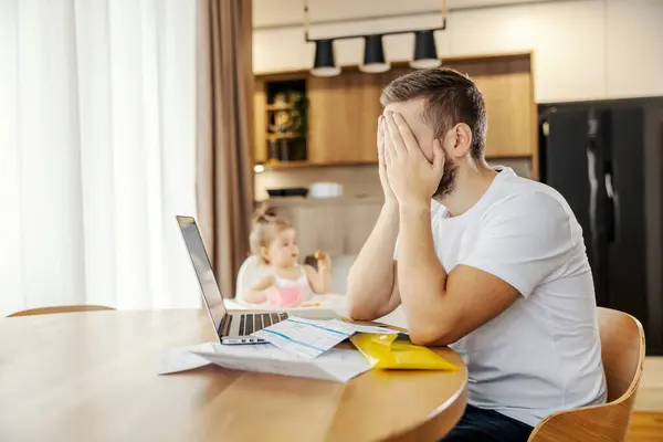 一个悲伤的男人在女儿玩耍的时候 在家里付账时遇到了麻烦 — 图库照片