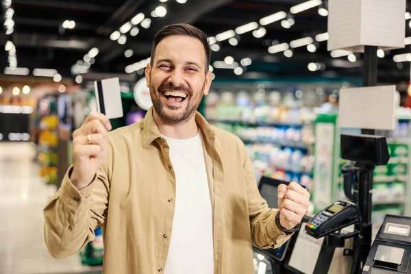 Elinde Kredi Kartıyla Gülümseyen Süpermarkette Kameraya Gülümseyen Bir Adam — Stok fotoğraf