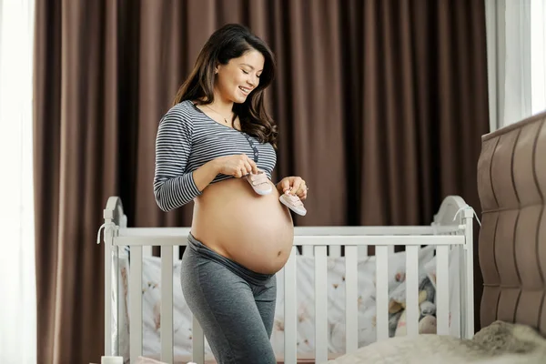 Mutlu Hamile Bir Kadın Karnını Yatak Odasında Beşiğin Yanında Gösterirken — Stok fotoğraf