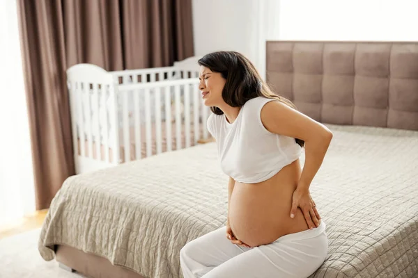 Een Zwangere Vrouw Fronst Heeft Rugpijn Terwijl Een Bed Zit — Stockfoto