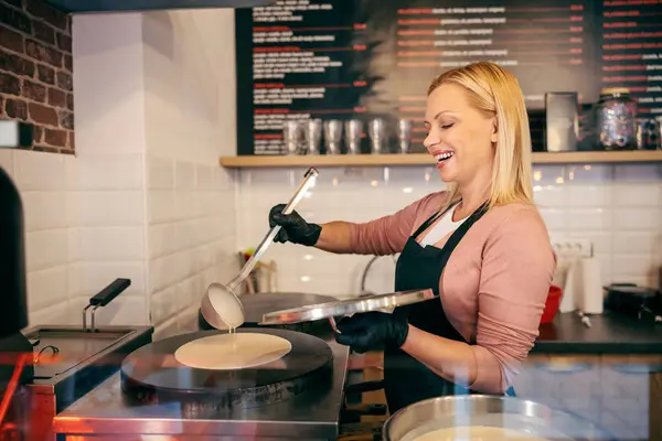 stock image A pancake house worker is baking flapjacks on hotplate and smiling at it.