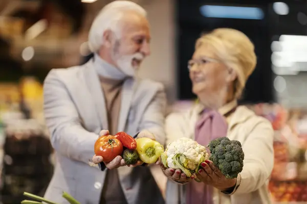 在超级市场的摄像机前选择性地聚焦老年人的手 展示蔬菜 — 图库照片