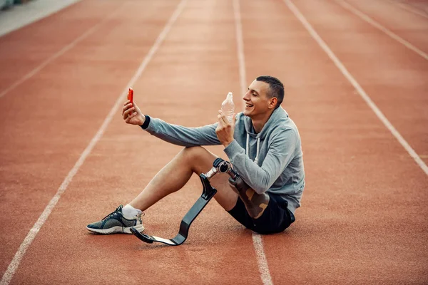 Protez Bacaklı Mutlu Bir Sporcu Stadyumda Bir Şişe Suyla Selfie — Stok fotoğraf